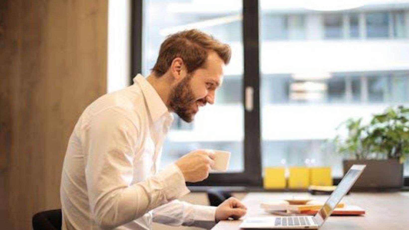 A man sitting in his office, looking at his laptop